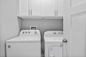 Laundry area featuring cabinets and washer and clothes dryer