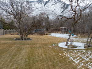 Snowy yard featuring a mountain view and a playground