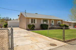 Ranch-style home with a garage, an outdoor structure, and a front lawn