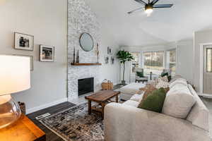 Living room featuring a fireplace, high vaulted ceiling, dark hardwood / wood-style floors, and ceiling fan