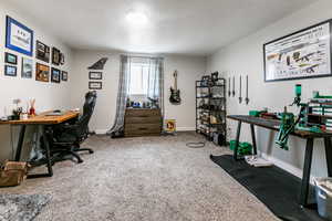 Carpeted home office with a textured ceiling