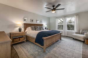 Bedroom with dark colored carpet, ceiling fan, and a textured ceiling