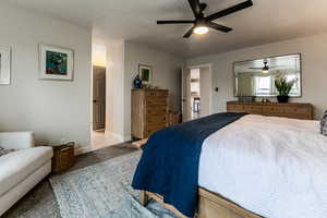 Carpeted bedroom with ceiling fan and a textured ceiling