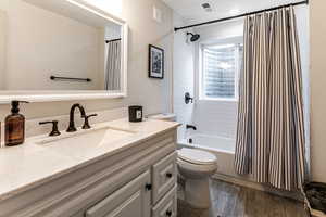 Full bathroom featuring wood-type flooring, toilet, vanity, and shower / tub combo with curtain