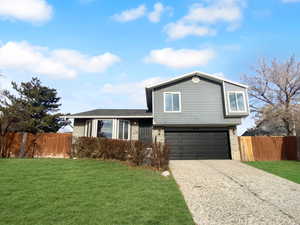 Tri-level home featuring a garage and a front lawn