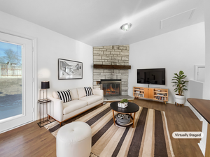 Living room with a stone fireplace and hardwood / wood-style floors