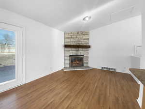 Unfurnished living room featuring hardwood / wood-style floors and a stone fireplace