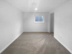 Empty room featuring a drop ceiling and carpet