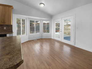 Unfurnished dining area featuring lofted ceiling, hardwood / wood-style flooring, and french doors