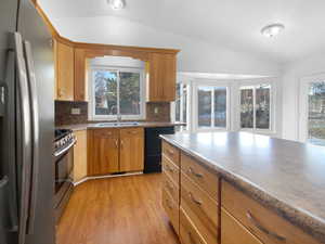 Kitchen with stainless steel appliances, sink, vaulted ceiling, and light hardwood / wood-style flooring