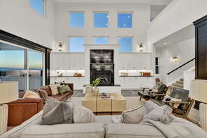 Living room with hardwood / wood-style flooring, a towering ceiling, and fireplace.