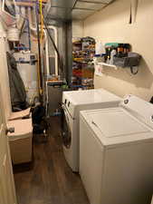 Washroom with independent washer and dryer, dark hardwood / wood-style flooring, and water heater