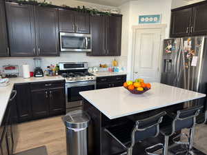 Kitchen with a center island, backsplash, a kitchen bar, appliances with stainless steel finishes, and light wood-type flooring