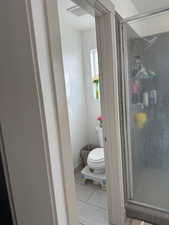 Bathroom featuring tile patterned flooring, a shower with shower door, and toilet