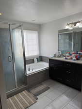 Bathroom featuring shower with separate bathtub, vanity, a textured ceiling, and tile patterned floors