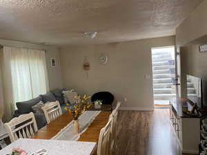 Dining space with dark hardwood / wood-style flooring and a textured ceiling