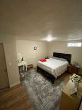 Bedroom with dark hardwood / wood-style flooring and a textured ceiling