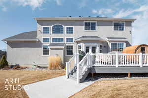 Back of property with a shingled roof, a deck, french doors, and stucco siding