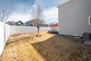 View of yard with a fenced backyard, a residential view, a deck, and cooling unit