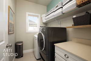 Clothes washing area with laundry area, light tile patterned floors, baseboards, and washer and dryer