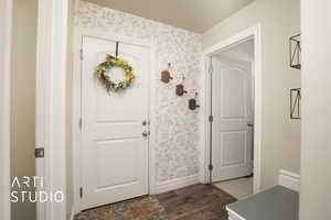 Interior space with baseboards, wood finished floors, and wallpapered walls