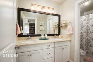 Bathroom with double vanity, a shower with curtain, toilet, and a sink