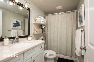 Bathroom featuring toilet, visible vents, a textured ceiling, and vanity