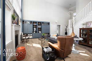 Living area featuring stairway, a notable chandelier, a fireplace, and a towering ceiling