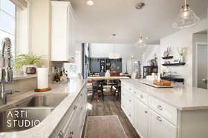 Kitchen with pendant lighting, white cabinets, and light stone countertops