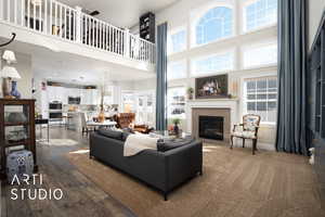 Living room with a towering ceiling, a wealth of natural light, dark wood-type flooring, and a glass covered fireplace