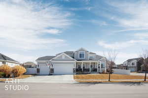 View of front of property featuring covered porch, an attached garage, board and batten siding, fence, and driveway