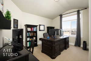 Home office with vaulted ceiling, baseboards, and light colored carpet