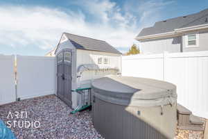 Exterior space with a storage unit, a fenced backyard, and a hot tub