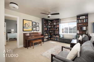 Living area with light carpet, ceiling fan, baseboards, and a textured ceiling