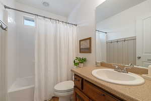 Full bathroom featuring shower / bath combination with curtain, vanity, and toilet