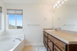 Bathroom with tiled tub, vanity, and tile patterned floors