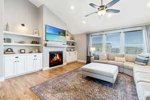 Living room featuring ceiling fan, lofted ceiling, and light wood-type flooring