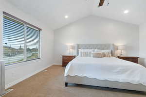 Bedroom with ceiling fan, vaulted ceiling, and light carpet