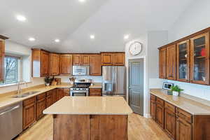 Kitchen featuring sink, light hardwood / wood-style flooring, stainless steel appliances, a center island, and light stone counters