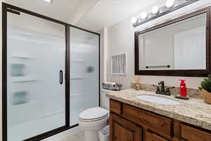 Bathroom with walk in shower, toilet, a textured ceiling, vanity, and tile patterned flooring