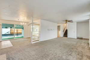 Unfurnished living room with carpet flooring and ceiling fan with notable chandelier