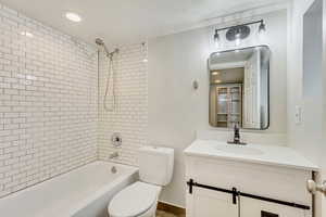 Full bathroom featuring vanity, toilet, a textured ceiling, and tiled shower / bath