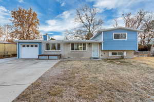 Tri-level home featuring a garage and a front lawn