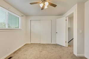 Unfurnished bedroom featuring light carpet, ceiling fan, and a closet