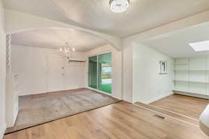 Foyer featuring hardwood / wood-style flooring, vaulted ceiling with skylight, a textured ceiling, and an inviting chandelier