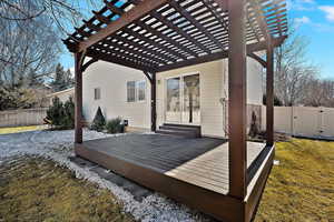 Wooden terrace featuring a pergola and a lawn