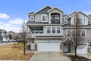 View of front facade featuring a garage, a front lawn, and a balcony