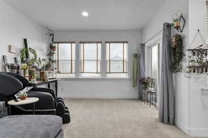 Interior space with light colored carpet and a textured ceiling