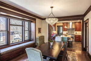 Dining room featuring radiator heating unit, ornamental molding, a chandelier, and dark hardwood / wood-style flooring