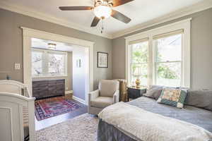 Bedroom featuring multiple windows, crown molding, hardwood / wood-style floors, and radiator heating unit